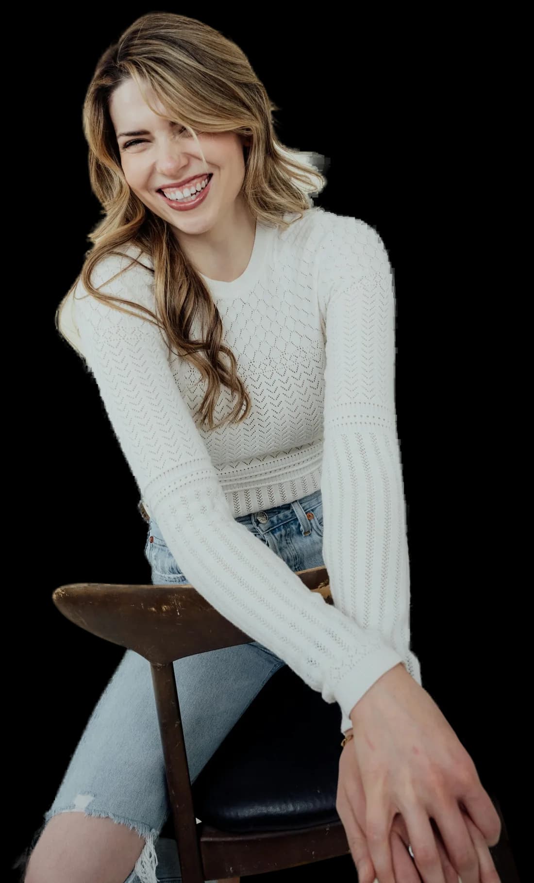 Mujer sonriendo, con suéter de punto y jeans